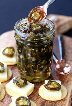 a jar filled with jelly and crackers on top of a wooden cutting board