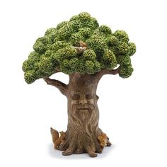 a figurine of a tree with green leaves on it's trunk and face