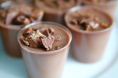 four cups filled with chocolate pudding on top of a white plate