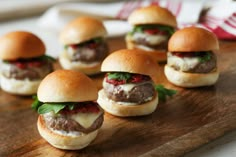 mini burgers with meat and cheese are arranged on a cutting board, ready to be eaten