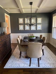 a dinning room table with chairs and pictures on the wall above it, along with a rug