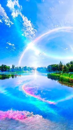 a large rainbow is in the sky over a body of water with trees and grass