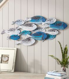 a blue and white metal fish sculpture on a wall next to a potted plant