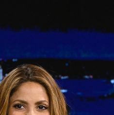 a woman with long hair smiling at the camera in front of a cityscape