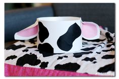 a cow print paper cup sitting on top of a bed