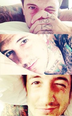 three men with tattoos and piercings laying in bed