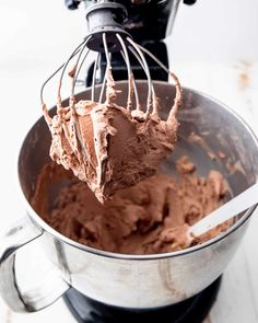 a mixer filled with chocolate frosting on top of a table