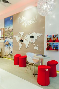 the interior of a children's playroom with red and white chairs, a world map on the wall