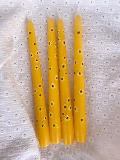 Four yellow candles lay on a white embroidered tablecloth. The dinner candles are painted with yellow sunflowers. Candle Wax Painting Ideas, Hand Painted Candles Diy, Candle Painting Ideas, Candle Painting Art, Paint Candles, Hand Painted Sunflowers, Painted Sunflowers