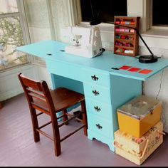 a sewing machine sitting on top of a blue desk next to a chair and window