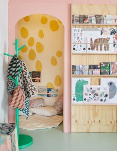 a room with pink walls and yellow polka dots on the wall next to a bed