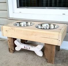 two metal bowls are on a wooden stand with a bone shaped sign underneath it that says alf