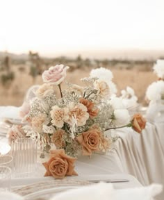 the table is set with white and peach flowers, champagne glasses, and napkins