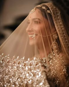 a woman in a wedding dress and veil smiling at the camera with her face covered by gold sequins