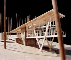 a wooden structure sitting on top of a sandy beach next to tall poles and poles