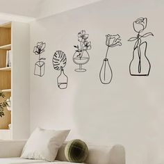 three vases with flowers in them are on the wall next to a white couch