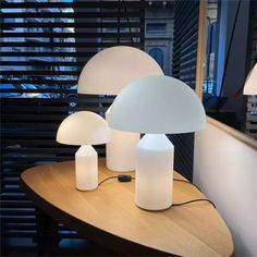 three white lamps sitting on top of a wooden table