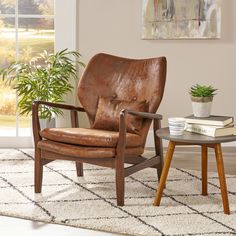 a brown leather chair sitting next to a table with a potted plant on it