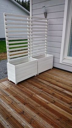 a white planter sitting on top of a wooden deck next to a window and door