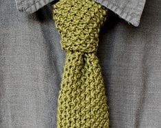 a man wearing a green crocheted tie with grey shirt and gray button down shirt