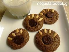 four cookies are on a plate next to a glass of milk