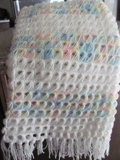 a white crocheted blanket sitting on top of a wooden table