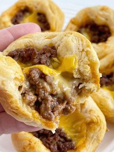 a hand is holding a sausage and cheese crescent pastries with melted cheese on top