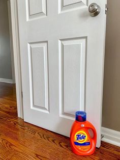 a bottle of tide liquid sitting on the floor next to a door with a handle