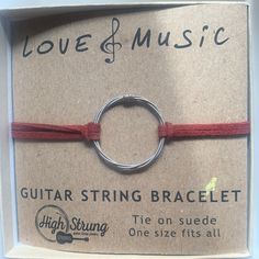 a red string bracelet with a silver ring on it's end in a cardboard box