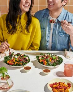 two people sitting at a table with plates of food