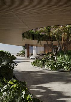 the building is surrounded by lush vegetation and palm trees, with cars parked in the driveway