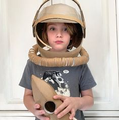 a young boy wearing a space suit and holding a coffee cup in front of his face