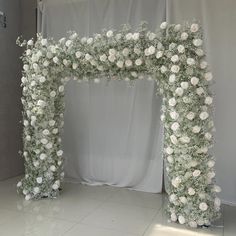 a white wedding arch decorated with flowers and greenery