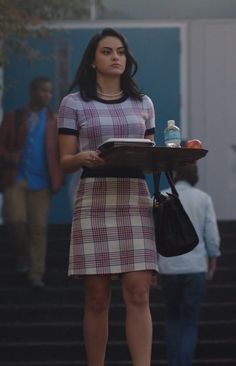 a woman in a plaid dress holding a tray