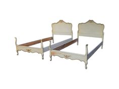 two white beds sitting next to each other on top of a bed frame with wooden slats