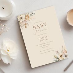 a baby shower is shown next to some candles and flowers on a white tablecloth