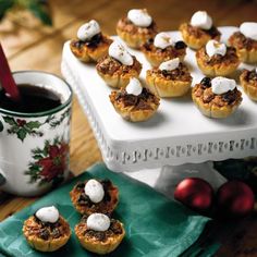 mini pies with marshmallow toppings on a white tray next to a cup of coffee