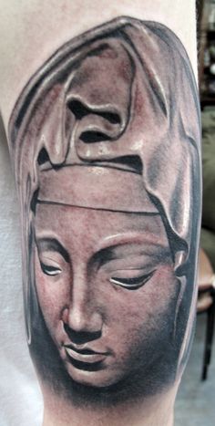 a man's arm with a black and grey tattoo design on it, depicting a buddha head