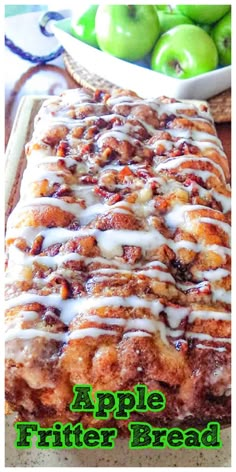 an apple bread with white icing and green apples in the background