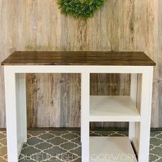 a white table with a green wreath on the wall above it and a rug underneath