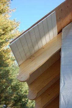 a close up of a wooden structure with a sheet on it's side and trees in the background