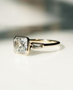 an engagement ring with two baguets on the side and a diamond in the middle