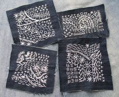 four pieces of black cloth with white designs on them, sitting next to each other