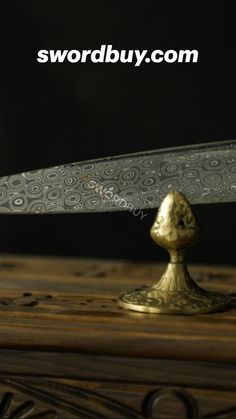 a knife that is sitting on top of a wooden table in front of a black background