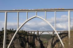 a train is traveling over a bridge with mountains in the background