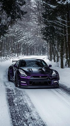 a purple sports car driving down a snow covered road in front of some tall trees