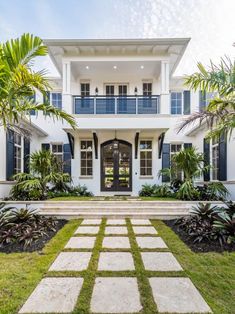 a large white house with blue shutters and palm trees in the front lawn area