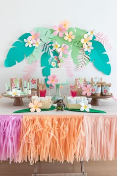 a table topped with cake and desserts covered in paper flowers