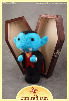 a small blue stuffed animal in a wooden box