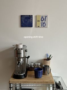 a coffee maker sitting on top of a wooden counter next to a basket filled with cups